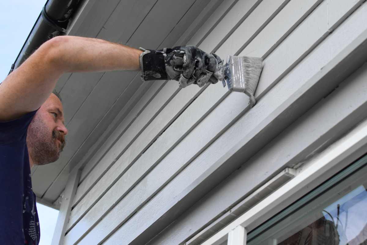 Painter painting the exterior of a gray home